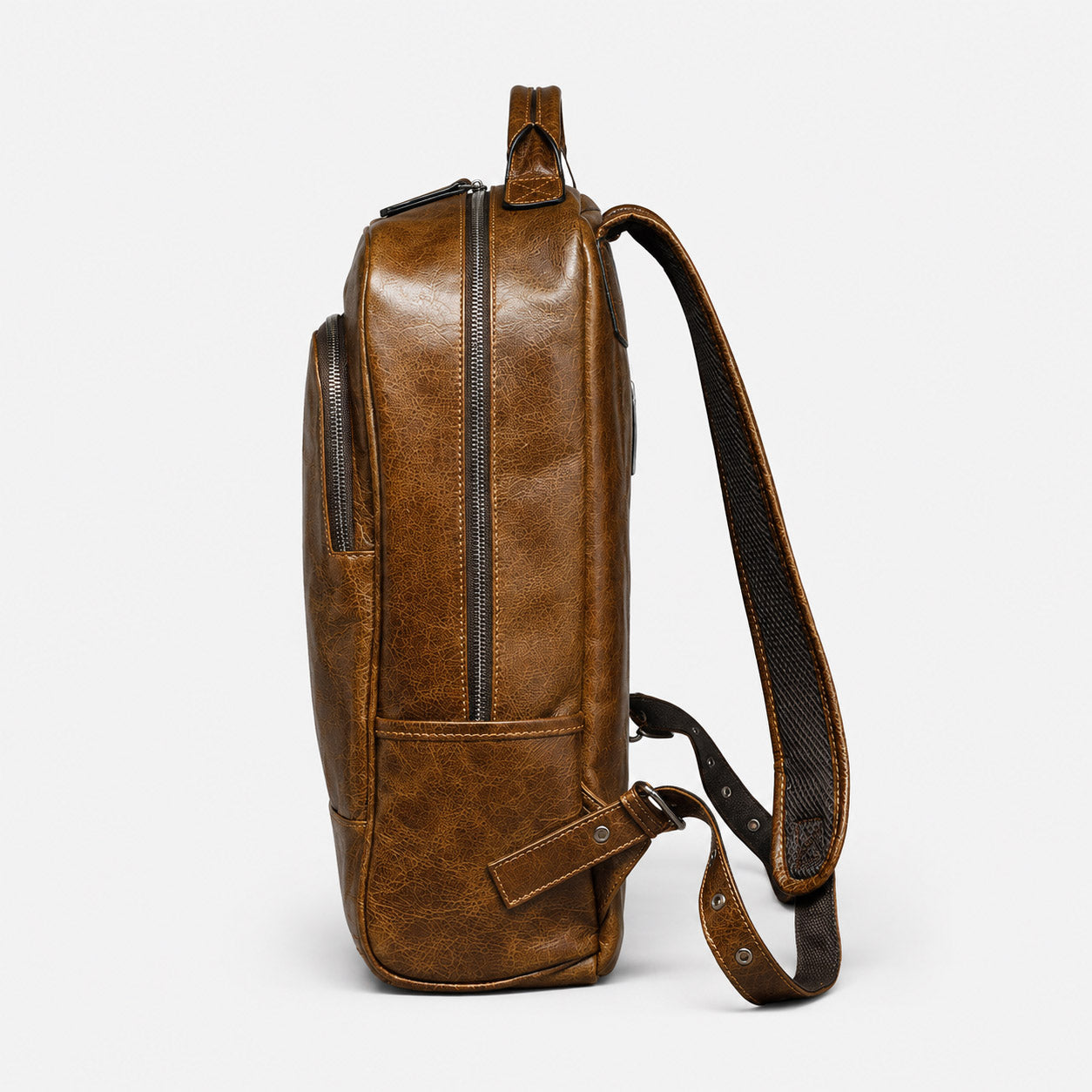 Side profile of leather commuter backpack showing side pocket and full-length zip