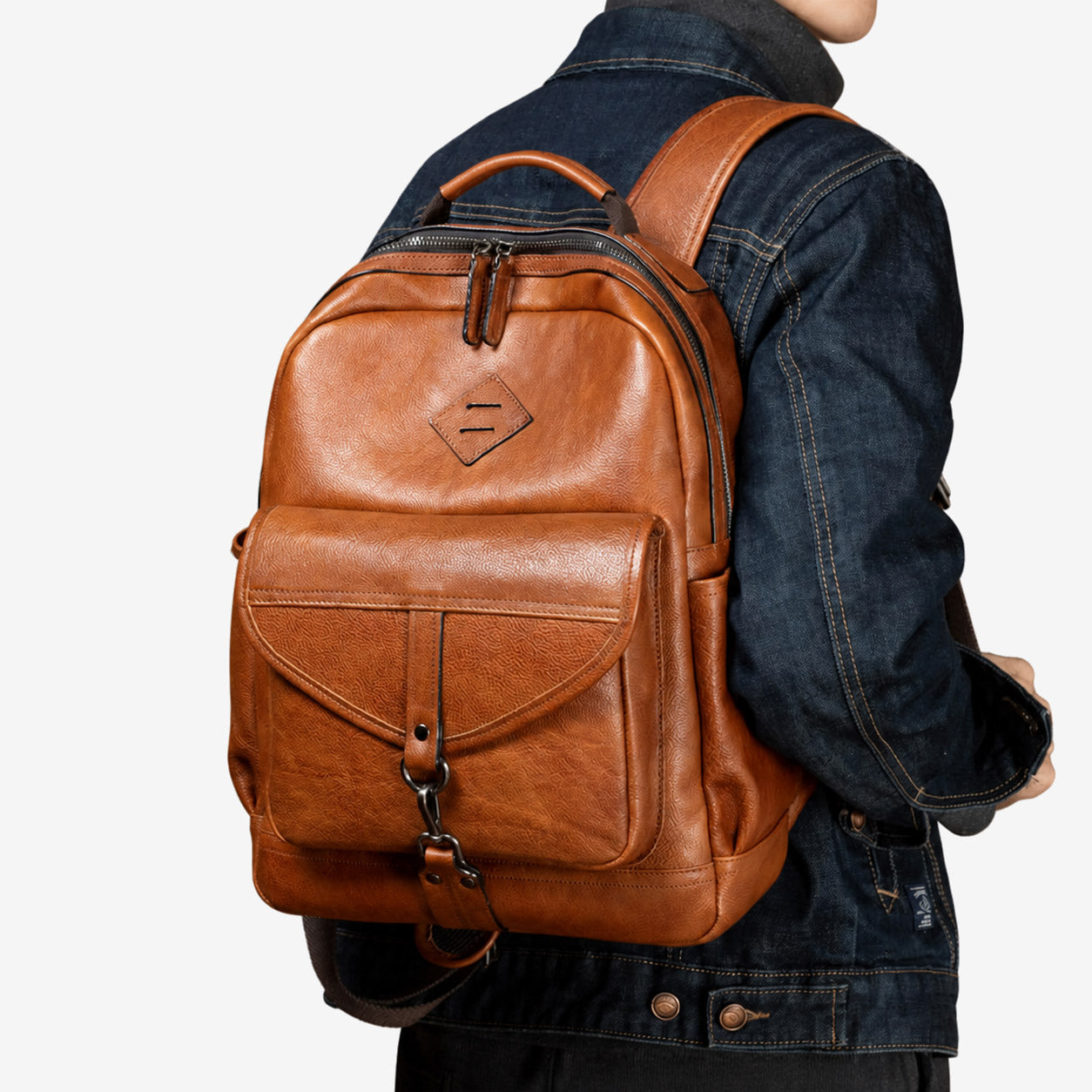 Man wearing the light brown leather backpack over a denim jacket